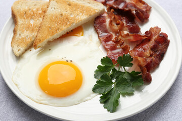 Delicious breakfast with sunny side up egg on light table, closeup