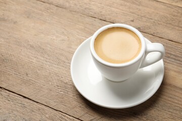 Aromatic coffee in cup on wooden table. Space for text