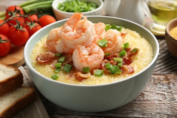 Fresh tasty shrimps, bacon, grits and green onion in bowl on wooden table, closeup