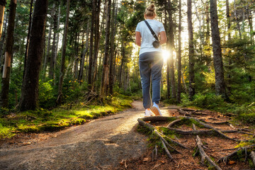A girl tourist walks along a rocky path with roots from trees in a magical fairytale forest. View...