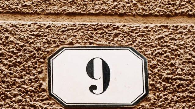 Number 9 (nine) affixed to the exterior of a building, with an elegant, vintage and traditional appearance