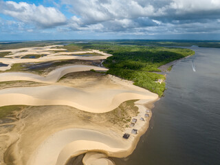 Naklejka premium Aerial view of Parque da Dunas - Ilha das Canarias, Brazil. Huts on the Delta do Parnaíba and Delta das Americas. Lush nature and sand dunes. Boats on the river bank 