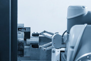 The automatic  robotic arm gripping the metal parts from CNC lathe machine.