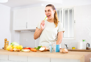 Dreamy girl in with vegetable on table in kitchen