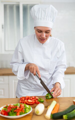 Female chef preparing vegetable salad, cutting vegetables