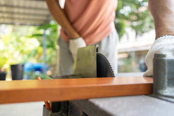 Close up Hand of man use an electric saw to cut aluminum with a wood pattern. Selective focus at saw.
