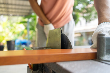 Close up Hand of man use an electric saw to cut aluminum with a wood pattern. Selective focus at...