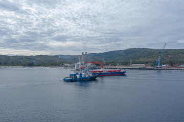 Tugboat escorts cargo ships entering the port