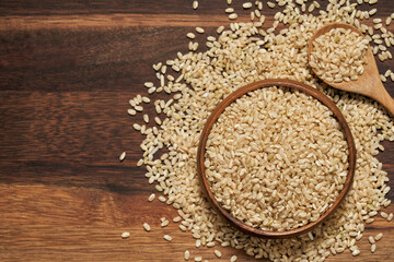 top view flat lay dry brown short grain rice in wood bowl on wooden table food background.