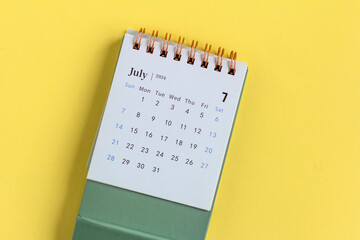 Desk calendar for July 2024 on a yellow background.