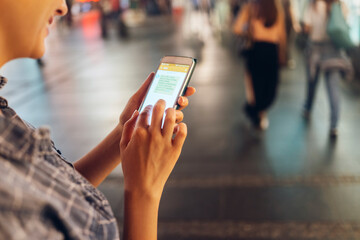 Young woman using smartphone downtown in the city at night