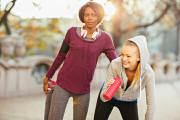Two women stretching after running in urban environment
