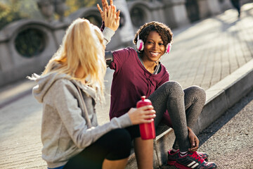 Obraz premium Two women high fiving while resting after a workout outdoors