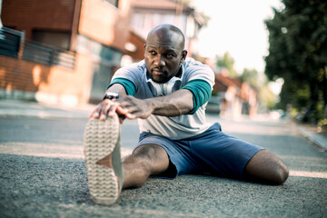 Active young black man stretching on the street