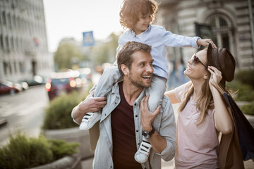 Joyful family with young child shopping and walking in the city