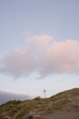 Wind Turbine on top of a dune with the moon behind it in sunset light. 