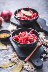 Pickled red onions in bowl on a gray background. Appetizer, condiment or topping, healthy fermented food