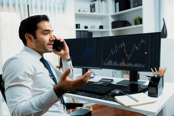 Trader businessman calling to consultant or partner with two stock exchange investment, compare...