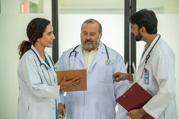 Multidisciplinary teamwork Three doctor hold clipboard document file of patient record talking...