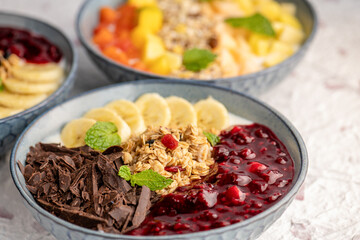 Three bowls of yogurt with various toppings.