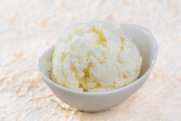 A scoop of vanilla ice cream in a white bowl.