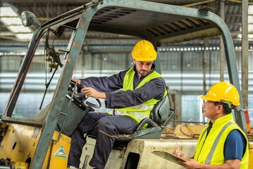 Portrait of forklift truck driver man smiling in old factory warehouse lifting pallet in storage shipping. forklift truck driver mail inside old forklift smiling to worker employee in warehouse store.