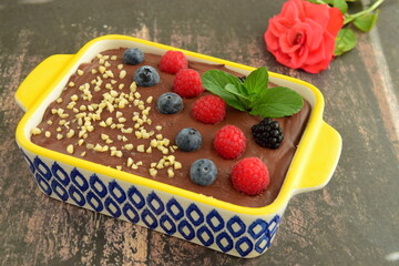 Homemade oatmeal tiramisu with melted dark chocolate topped with fresh berries, chopped almond and mint leaf on serving dish