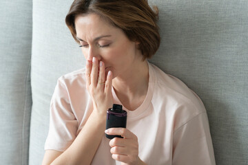 Young woman using disposable electronic cigarette during work on laptop at home	