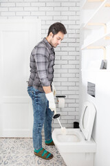 Сlose-up shot of a man cleaning a toilet using a special cleaning product and a brush