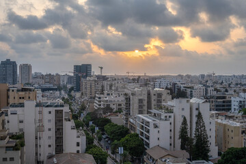 Sunset over the sea in the city of Herzliya, with buildings and construction cranes