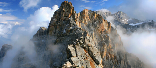  A dramatic mountain peak rising into the clouds, with rugged cliffs and sheer rock faces, the...