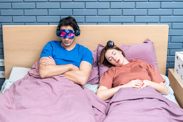Young annoyed man can't sleep because his wife in snoring	