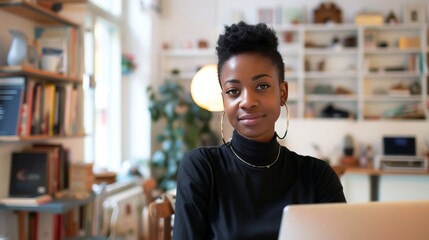 Beautiful young black woman smiling at camera while seated behind her personal computer
