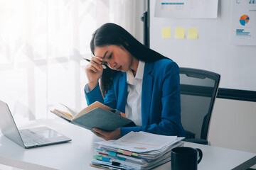 Asian woman feeling migraine head strain.Overworked businesswoman financier while working on laptop...