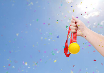Holding a gold medal  celebrating success sky background