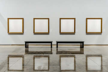 the elegant gallery hall adorned with four wooden frames, each encasing a white canvas, hung above a sleek, black bench exhibit
