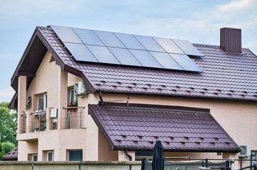House with solar panels on rooftop for generating electricity through photovoltaic effect. Home...