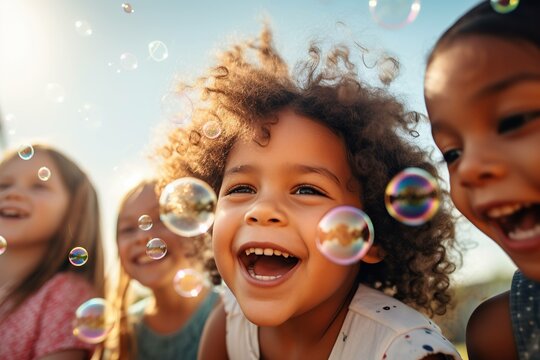 Multi-ethnic group of little friends with toothy smiles on their faces enjoying warm sunny day while participating in soap bubbles show