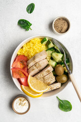 Healthy salad with chicken, tomato, cucumber, olives and rice in bowl on white background with copy space
