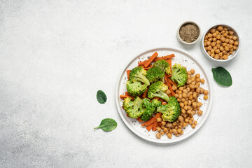 Healthy food broccoli, carrots and chickpeas on a plate top view on a white background with copy...
