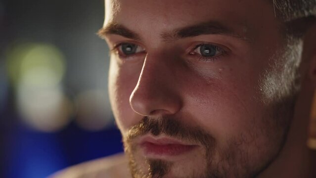 Close up shot young bearded man looking at computer monitor. Stressed ukrainian migrant watching war crime. Serious focused guy see bad news in internet. War in Ukraine flashbacks