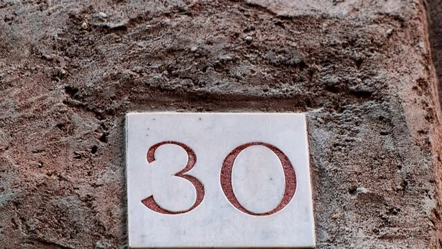 Number 30 (thirty) affixed to the exterior of a building, with an elegant, vintage and traditional appearance