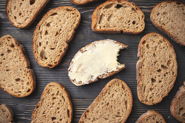 Sliced whole grain bread with a buttered piece