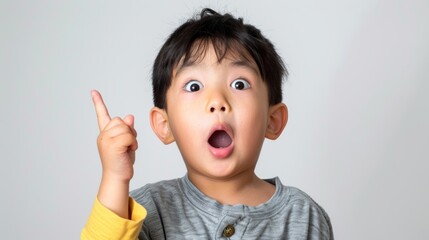 A little Chinese boy with a surprised expression, pointing upwards, exaggerated expression, white background