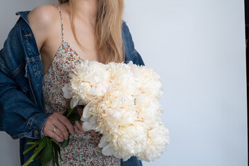 Happy woman holding white peonies in her hands. The florist girl collected a bouquet of peonies....