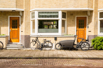 Two doors of two houses in Amsterdam, Netherlands. There are bikes parked on the street.