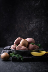 Raw uncooked potato on dark table