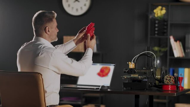 A doctor or scientist holds and views plastic 3d printed model of human mandible. A sketch of heart in red colour on a laptop screen. The concept of bioprinting organs for prosthetics and transplants