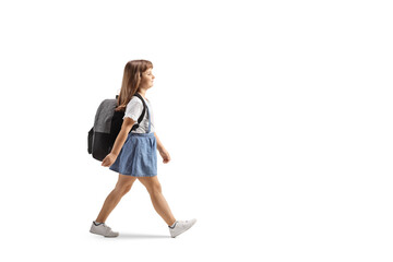 Full length profile shot of a little girl with a backpack walking
