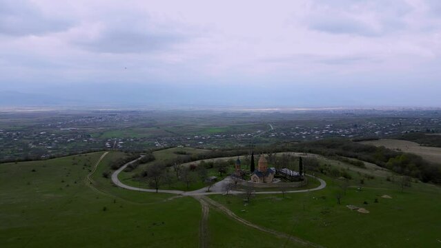 lonely ancient church in the mountains between green hills, aerial view